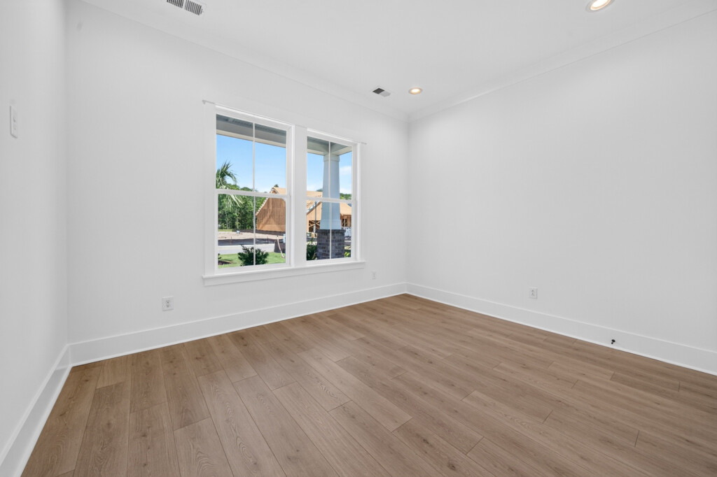 Empty bedroom with light wood-look plank flooring in a new Sanderling Bay home