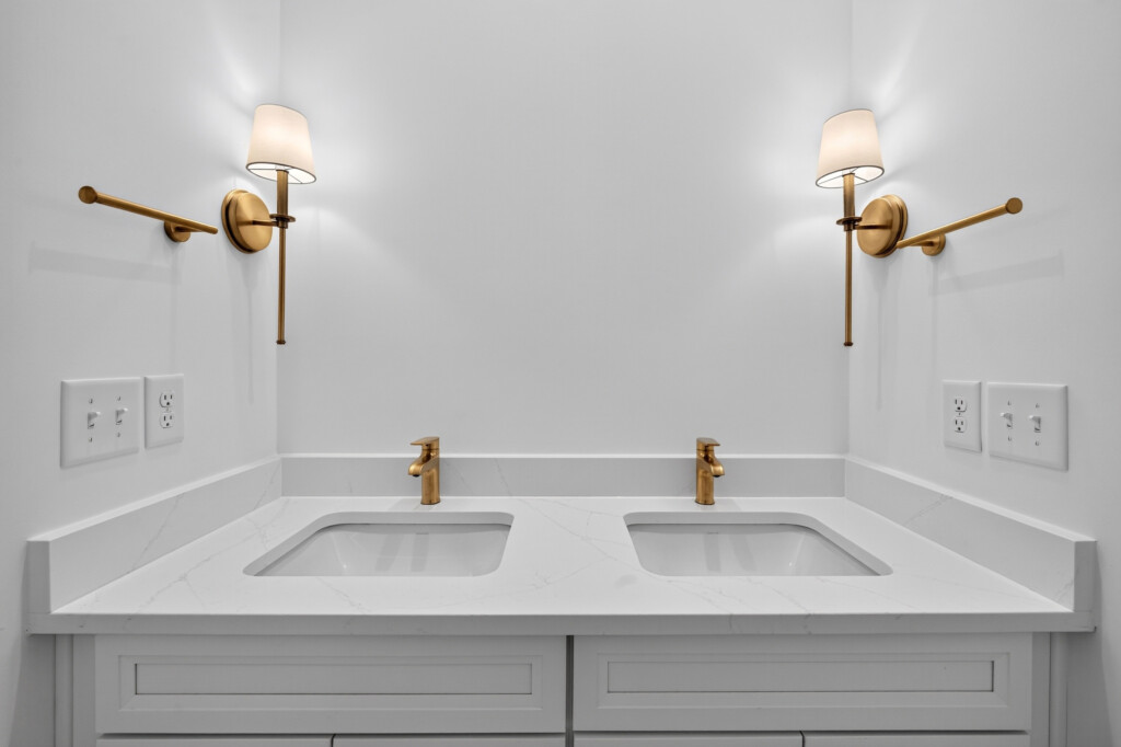 Double vanity with brass sconces and quartz countertop