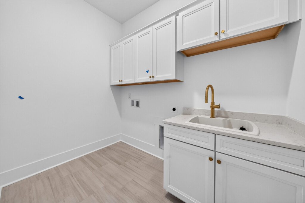 Laundry room with utility sink, white cabinets, and plank flooring