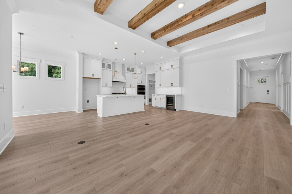 Sanderling Bay great room with exposed beams, kitchen and light wood-look plank flooring