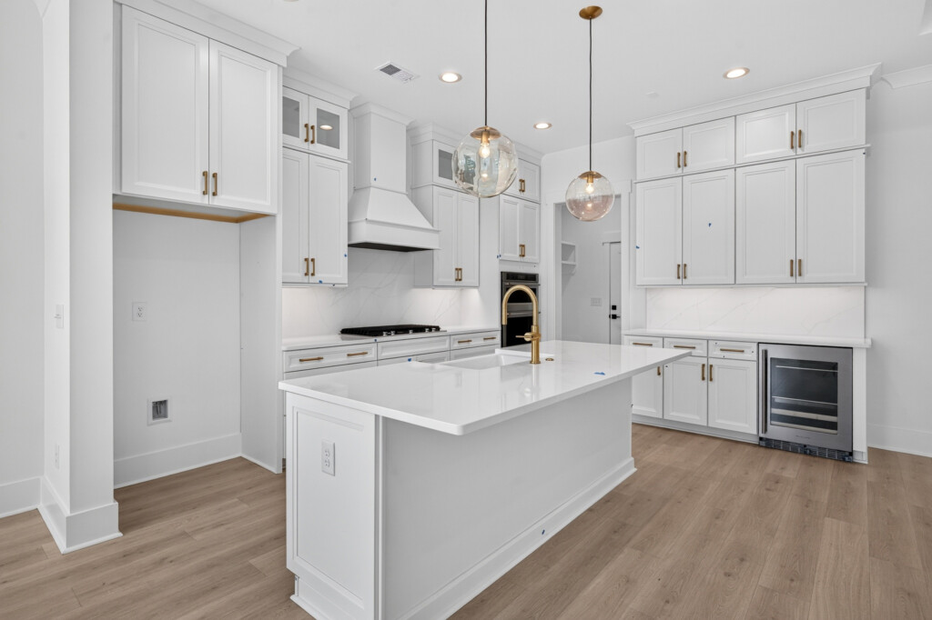 Sanderling Bay white kitchen island with pendants and light wood-look plank flooring
