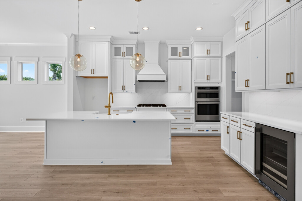 White kitchen with island, double wall ovens, and plank flooring