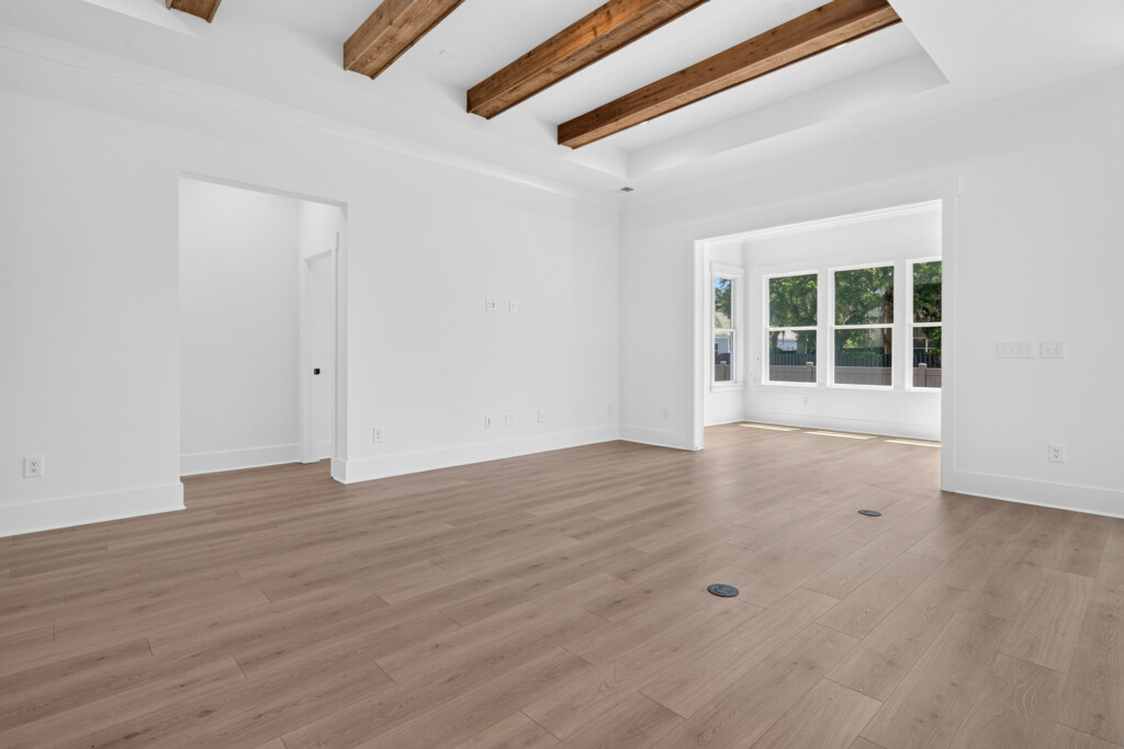 Empty living room with wood beams and light plank flooring