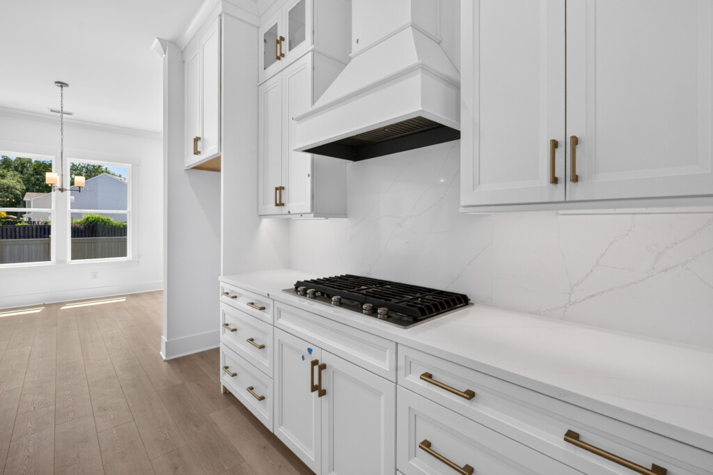 Kitchen range wall with quartz backsplash and white cabinets