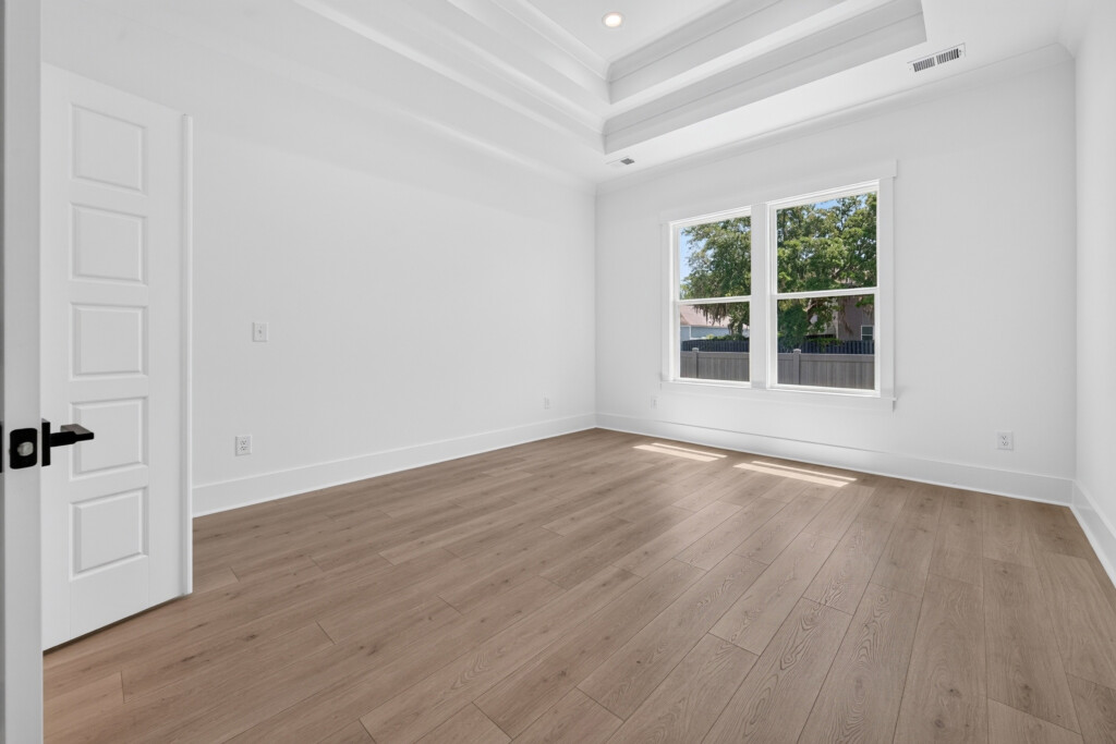 Bedroom with tray ceiling and light wood-look plank flooring