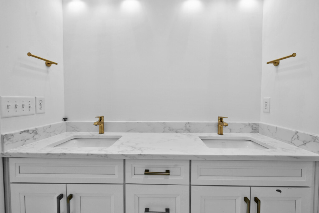 Double vanity with brass faucets and marble countertop