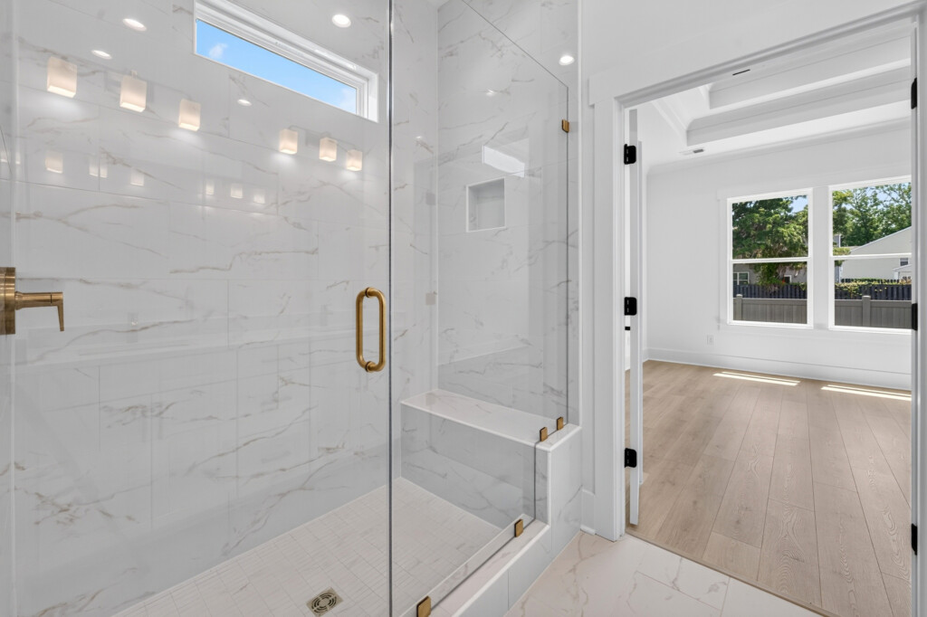 Glass walk-in shower with marble-look porcelain tile in a Sanderling Bay home
